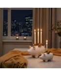 Set 4er-Kerzenständer Schwein weiss-gold aus Holz für Stabkerzen - Vor Fenster mit Stadt im Hintergrund in Nacht